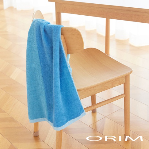 HARUKA 今治耐用絢彩拼接浴巾，藍色漸層，柔軟材質，垂掛於木質座椅上。