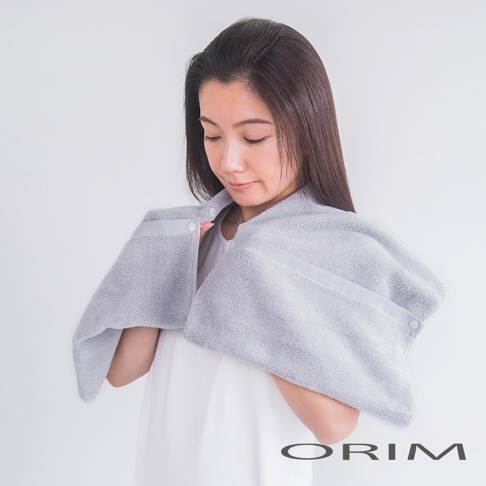 一位女性穿著淺灰色毛巾頭巾，頭巾由柔軟吸水材質製成，帶有兩個按鈕扣合。