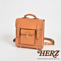職人手作皮革經典學院風迷你後背包，採用天然皮革製成，呈現焦糖棕色。包款設有翻蓋、金屬扣環與調節式皮帶，設計簡約而實用。