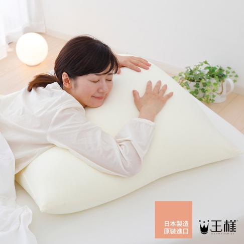 一位女性抱著一個米白色的巨大三角形枕頭，枕頭材質看起來柔軟蓬鬆。