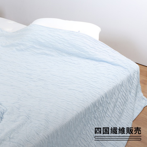 淺藍色舒芙蕾透氣涼被，無棉款，表面有細緻的壓紋，柔軟輕盈，鋪在床上。