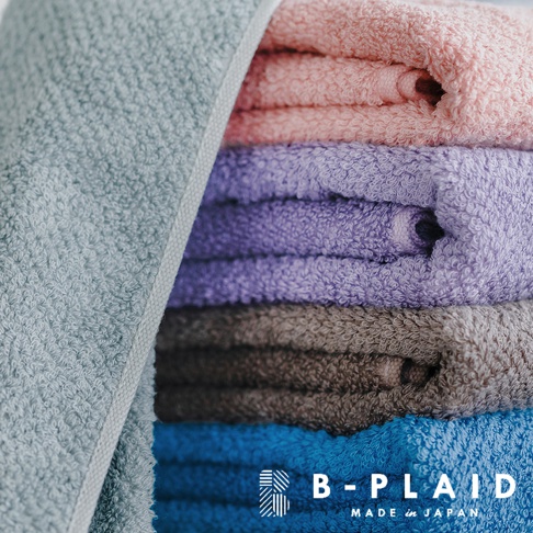 一疊五種顏色的今治浴巾，包括淡藍、粉紅、紫色、灰色和藍色。浴巾採用鱗紋織法，材質為柔軟的棉，質感細膩。