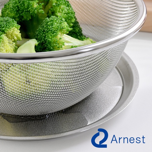 逸品物創不鏽鋼瀝水籃，網眼細密，搭配同色系圓形底盤，籃中盛有綠色花椰菜。