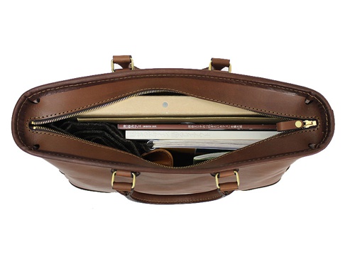 棕色皮革製成的職人手作兩用商務托特包，包包上方拉鍊部分敞開，內有書籍、文件夾及其他物品。