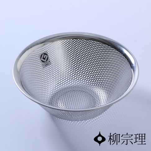一個銀色圓形不鏽鋼瀝水盆，盆身佈滿細小的圓孔，邊緣光滑，盆內有品牌標誌。
