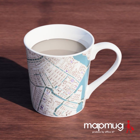 白瓷馬克杯，杯身上印有細緻的江戶古地圖，以淺藍色描繪河流和水域，搭配米白色底色及黑色、紫色線條標示街道與建築，附帶白色手把，杯中盛有淺棕色液體。