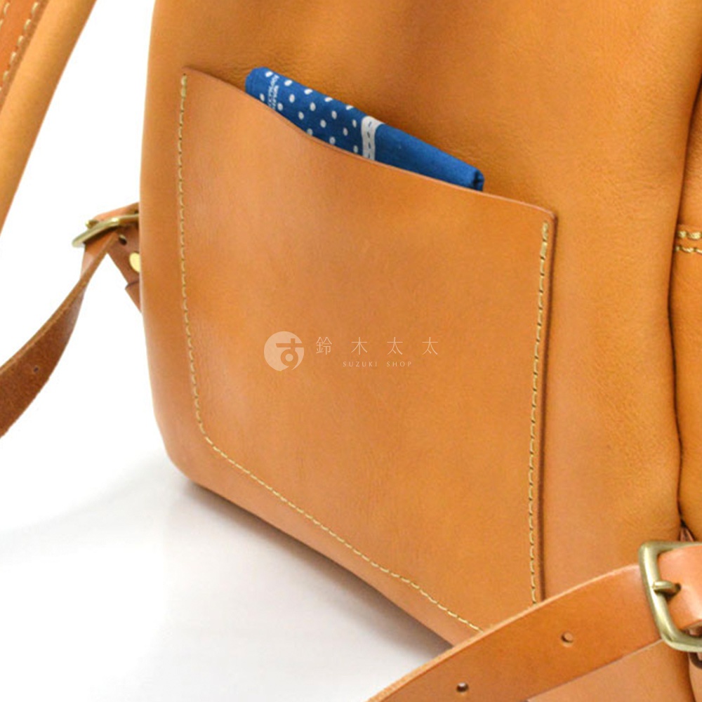 棕色皮革休閒風後背包，有外側口袋，口袋內裝有藍底白點圖案的布料。