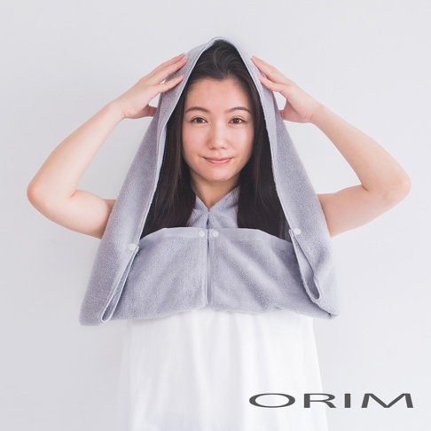 一位女性頭戴淺灰色毛巾布材質的吸水頭巾，頭巾連帽，前面有兩個白色按扣。