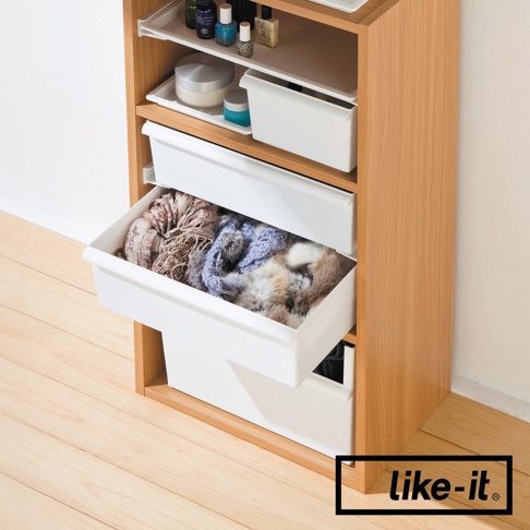 木製收納櫃中，兩個白色寬型收納盒，其中一個抽屜裝有圍巾和毛皮飾品，另一個抽屜則裝有化妝品。