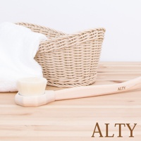 淺色木柄的長柄沐浴刷，刷頭為米白色細軟毛。旁邊擺放著一條白色毛巾和一個米色編織籃。