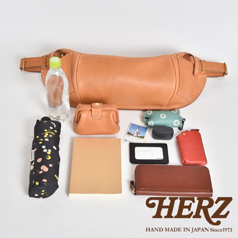 日本HERZ品牌，職人手作皮革大容量斜背包F-1，展示了包含水瓶、摺疊傘、零錢包、卡夾、耳機、長夾、筆記本等配件。