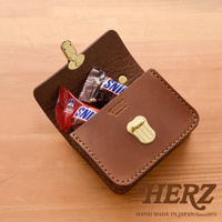 職人手作皮革迷你收納包，深棕色，展示打開的狀態，內有兩條巧克力。包包有金色扣環和品牌標誌，縫線整齊。