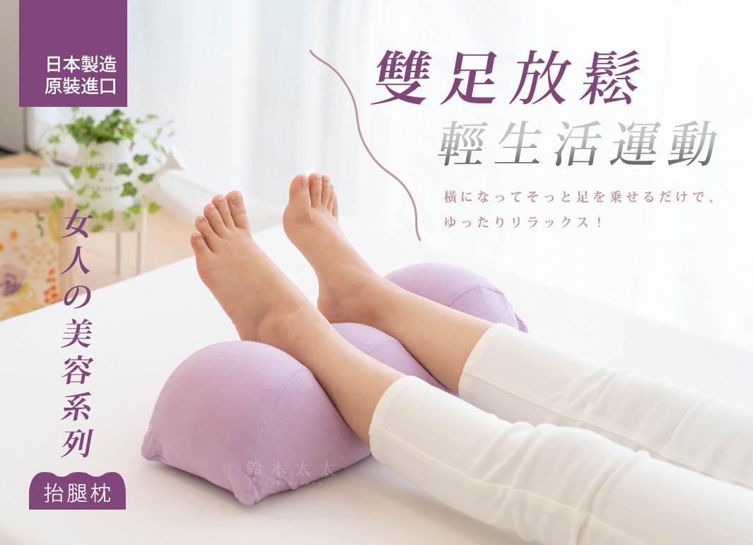 一雙淺紫色、織物材質的抬腿枕，支撐著模特兒的雙腳，雙腳平放在枕頭上，腿部穿著白色長褲。