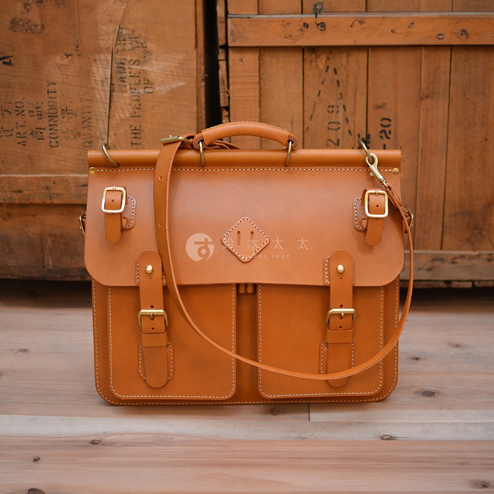 職人手作皮革旅行包 A-102，經典棕色，以全粒面皮革製成，配有金色搭扣和可調節肩帶，設計簡約實用。