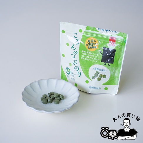 一包綠色包裝的鍵庄超微粉海苔錠，旁邊擺著一個白色小碟子，裡面裝著十幾顆綠色的小藥丸。