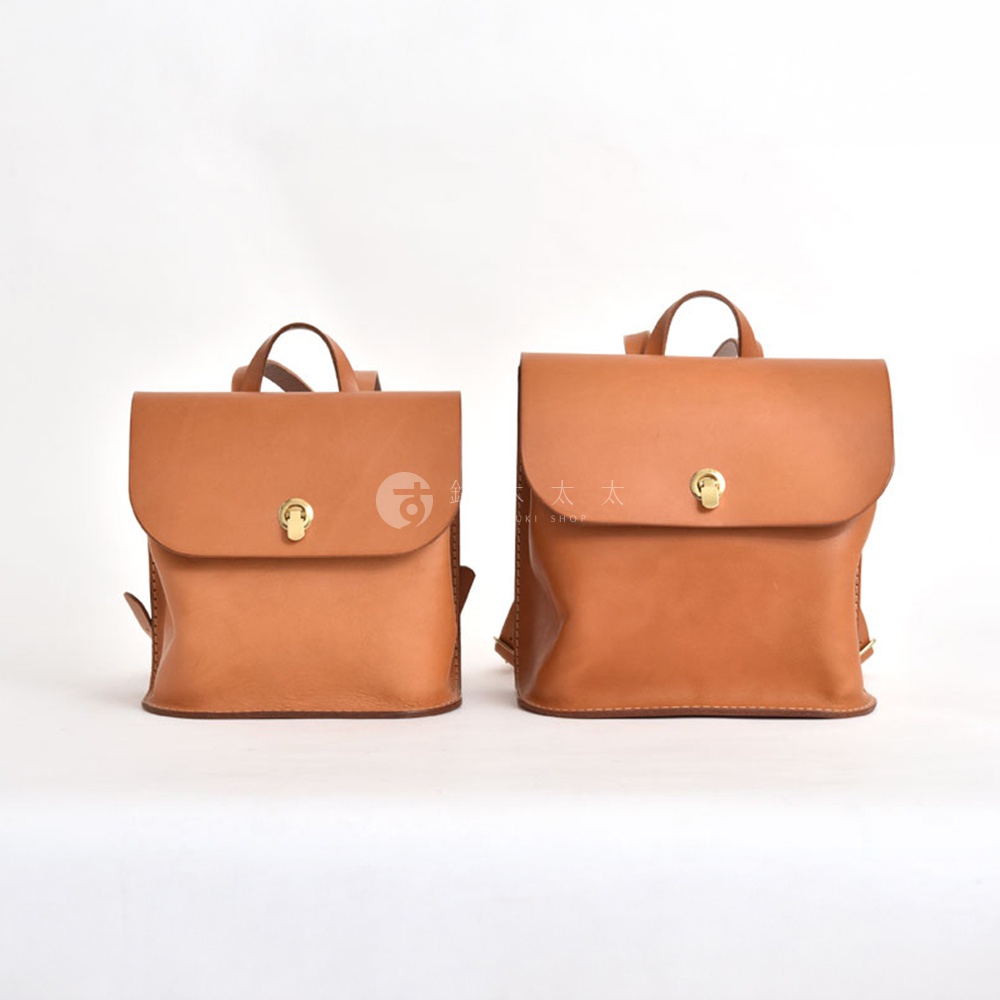 兩款棕色皮革翻蓋迷你後背包，皆有金色旋轉鎖扣，一個較小，一個較大，皆為職人手作。
