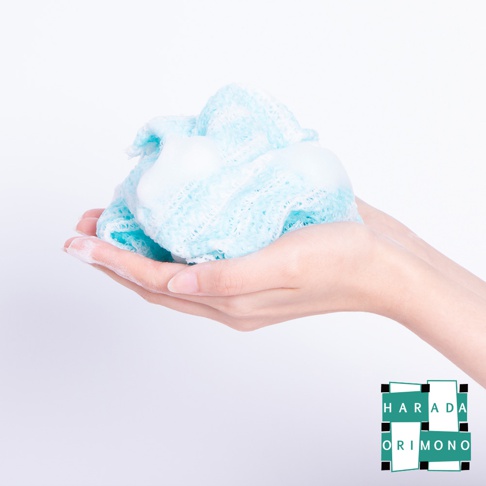 雙手捧著藍色網狀材質的泡泡洗澡巾，上面覆蓋著豐富的白色泡泡。