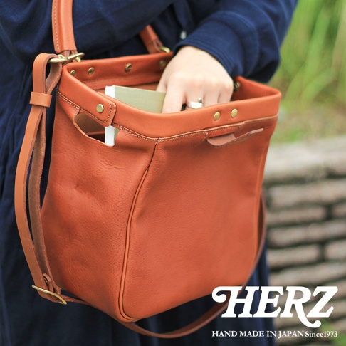 棕色皮革方形口金托特包，包身側面設有插袋，可單肩或斜挎，配有可調節長度的皮革背帶。