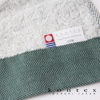 HERRINGBONE 今治長纖有機棉斜紋浴巾，採用綠色斜紋編織，搭配白色毛圈織物，質感細膩，並帶有品牌標籤。