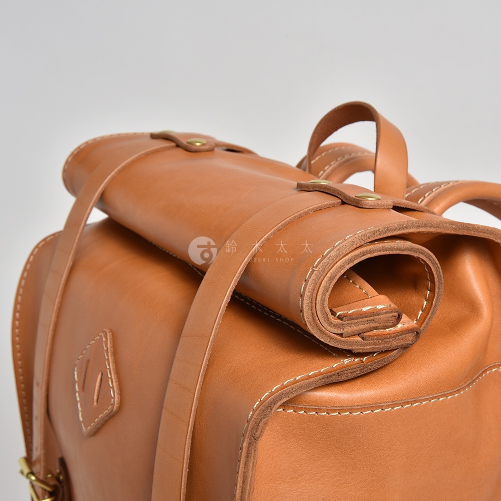 職人手作皮革露營登山用大容量後背包 R-19，使用棕色皮革製成，搭配白色縫線和金屬扣環，頂部有捲口設計和固定帶。