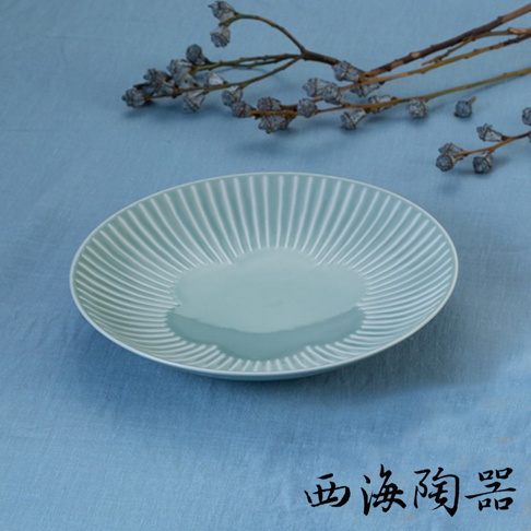波佐見燒花 FUWARI 兩件式主食盤，淡藍色陶瓷材質，盤面有放射狀的壓紋設計，中央略微凹陷，背景為藍色布料，上方有乾燥的枝條裝飾。