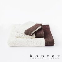 白色長纖有機棉毛巾堆疊，其中一條毛巾的邊緣飾有深棕色人字紋斜紋織帶。