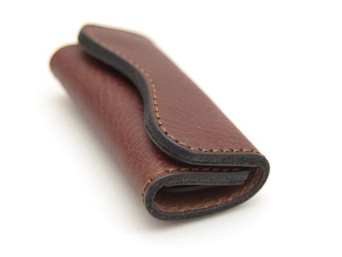 職人手作咖啡色荔枝紋皮革鑰匙包，以細緻縫線包邊，造型簡約，可容納多把鑰匙。