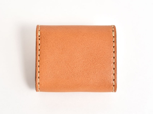 一個簡約的棕褐色皮革雙折收納零錢包，採用手工縫線裝飾，整體呈現質樸的設計風格。