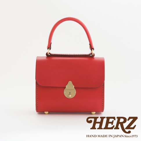 紅色皮革復古杜勒斯手提包，配有黃銅鎖扣和提把，底部有四個黃銅腳釘，整體造型簡潔大方。