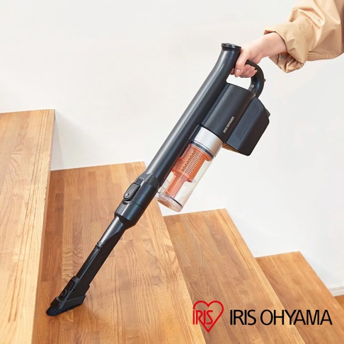 黑色無線手持吸塵器，配有透明集塵筒及橙色濾網，由手持於木製樓梯上。