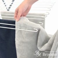 一隻手正將淺灰色、帶菱紋質感的純棉長毛巾掛在白色晾衣架上，旁邊還有一條深藍色長毛巾。