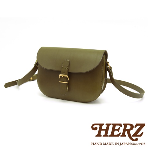 橄欖綠皮革經典馬鞍包，配有金色金屬釦環和可調式肩帶，設計簡約，展現職人手作質感。