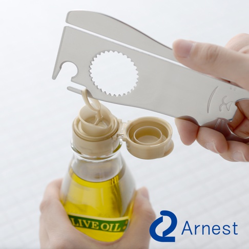 一只手握著的銀色金屬萬用開罐器，其上有多種尺寸的開口，正用於開啟一瓶裝有黃色液體的玻璃瓶。瓶蓋為米白色塑膠材質，已部分開啟。