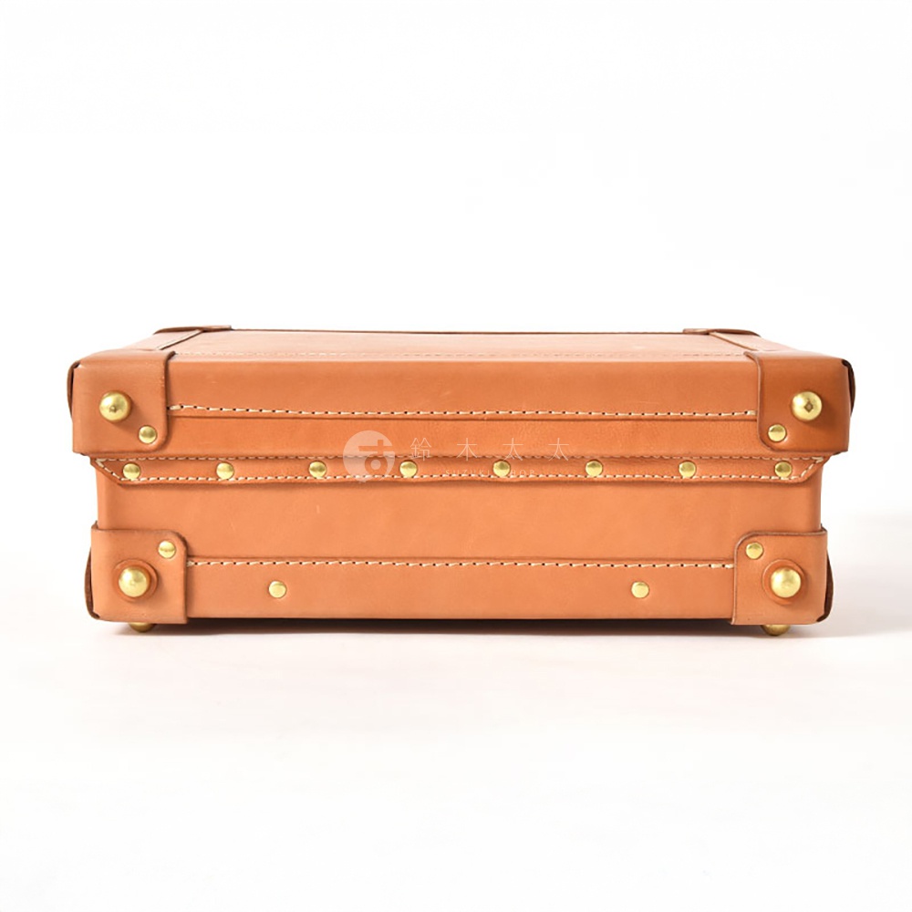 職人手作皮革英倫風便攜手提行李箱，採用光滑棕色皮革，搭配金色金屬邊角和鉚釘裝飾，呈現經典復古造型。箱體結構穩固，邊緣車線整齊。