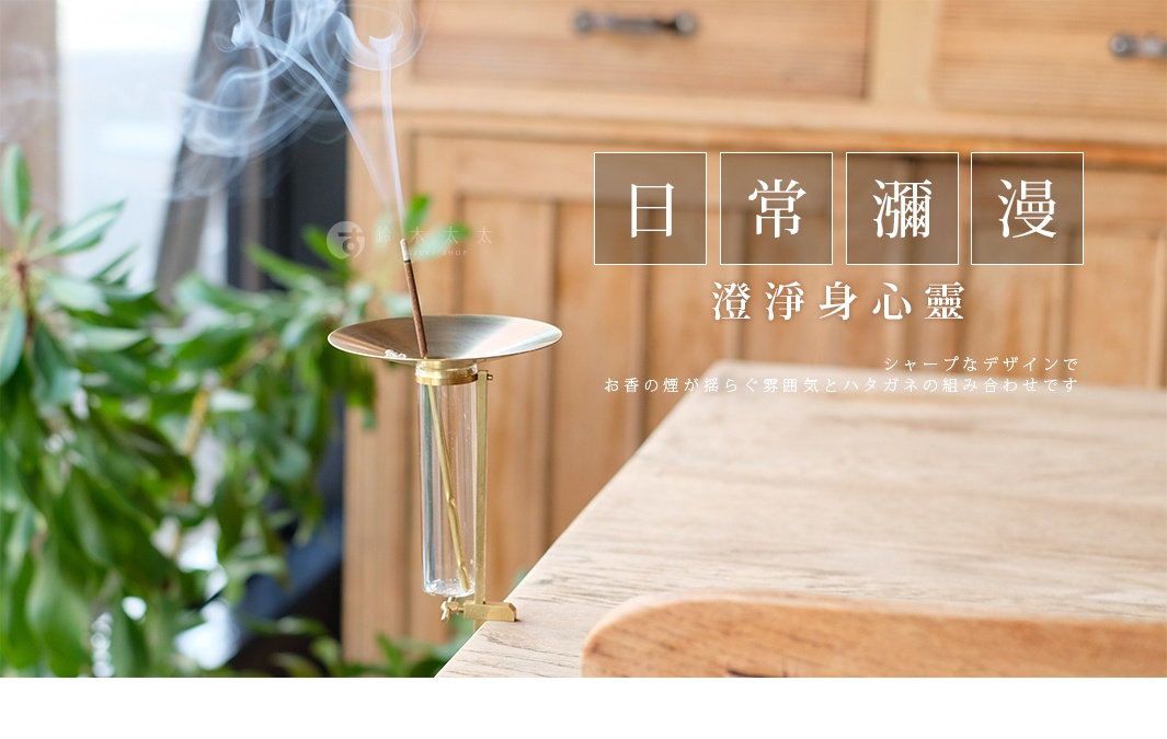 黃銅可夾式玻璃線香架，帶有圓形黃銅托盤和透明玻璃管，黃銅線香插在托盤中央，線香燃燒時冒出煙霧，整體結構精緻。