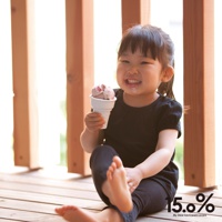 小女孩坐在木地板上，開心地拿著一個裝有粉紅色冰淇淋的白色甜筒杯，杯子下方是傳統的格紋甜筒。