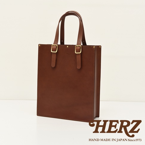 棕色皮革製成的方形托特包，配有兩條皮革提把，提把上裝有金色金屬扣環。