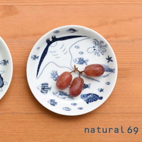 白色陶瓷小碟，繪有藍色線條的海洋生物圖案，包括蝠魟、章魚、海星和多種魚類。碟中擺放著一串紅色葡萄。