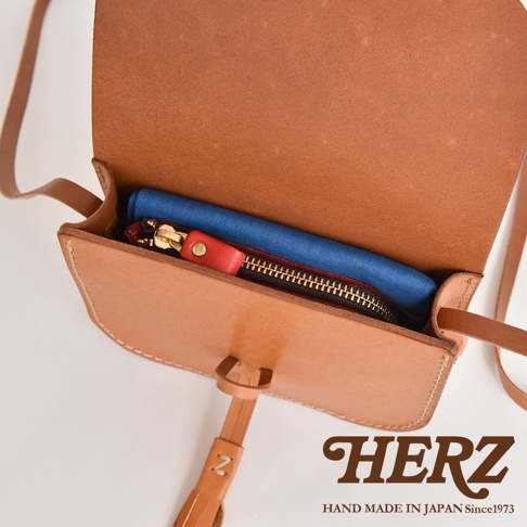 職人手作皮革流蘇側背包 CP-18，展示天然皮革的棕褐色，包內有藍色布料、黑色拉鍊零錢包，以及紅色皮革拉環。