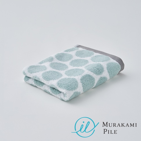 折疊的淺綠色和白色波點毛巾，帶有灰色滾邊，背景為白色。