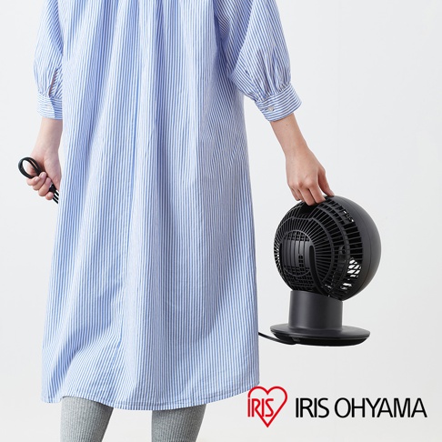 黑色圓形空氣循環扇，帶有黑色底座和網狀扇葉護罩，由一名身穿藍白條紋連衣裙的人士手持。