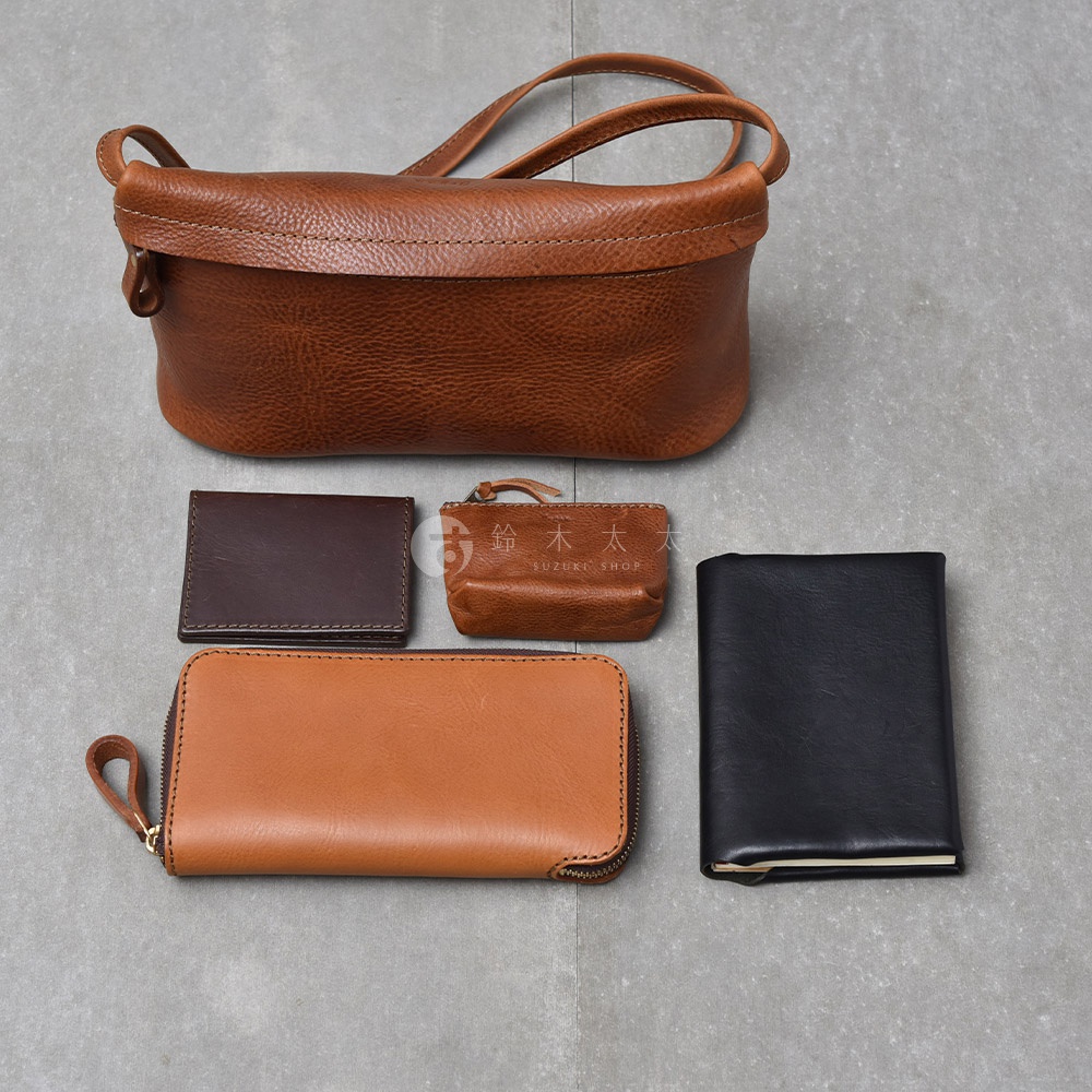 職人手作皮革Organ貼身斜背包M-8，包含一個棕色斜背包、一個深棕色名片夾、一個淺棕色零錢包、一個淺棕色長夾以及一個黑色筆記本。