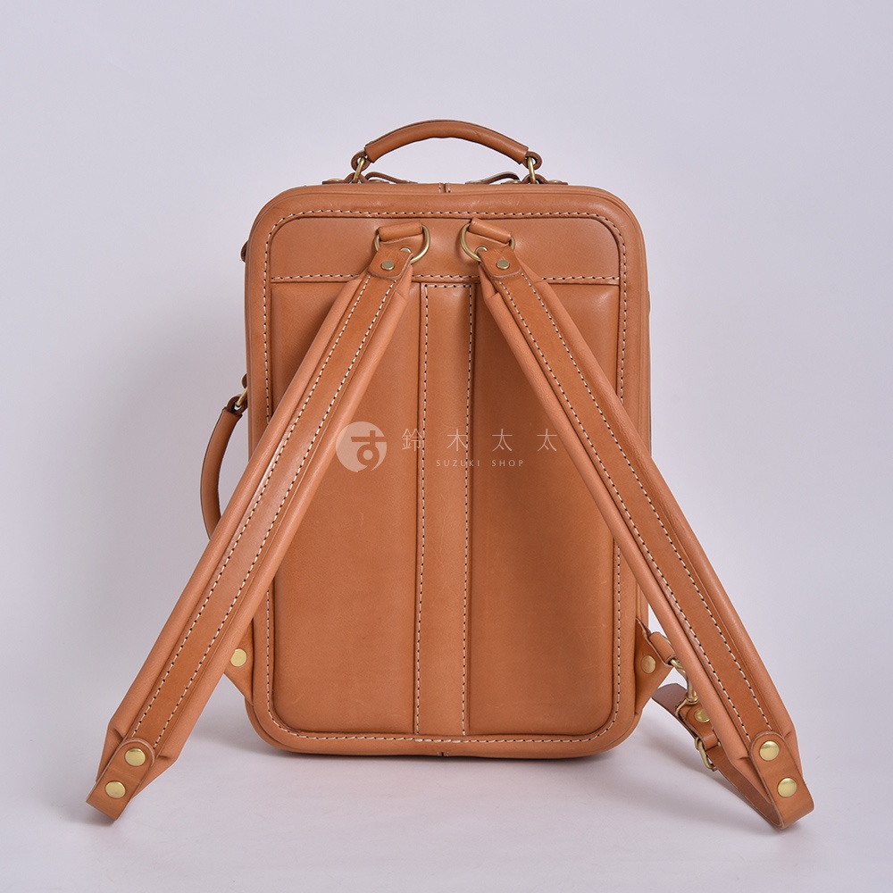 職人手作皮革兩用商務後背包，採用自然色皮革，設有兩個可調節的皮革肩帶，並配有金屬扣件，整體設計簡潔。