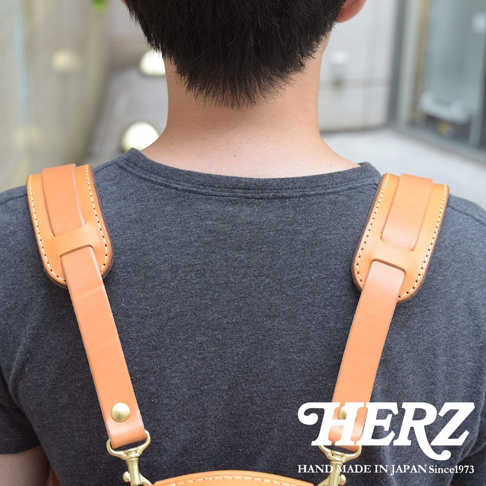 職人手作皮革肩墊，淺棕色全皮革製成，配有金屬扣環，展示於穿著灰色T恤的男性肩上。