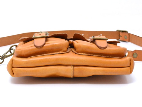 職人手作皮革水洗加工前雙口袋肩背包，呈現自然的淺棕色皮革，包身有兩個翻蓋式前袋，配備金屬扣環和可調式皮革背帶。