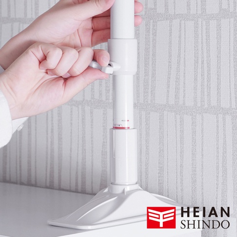 白色伸縮防傾桿，由塑膠材質製成，具有可調節的鎖定機制。底部為寬大的白色底座，能提供穩定支撐。