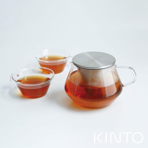 Carat 茶壺 600ml，透明玻璃壺身，配有不鏽鋼濾網和壺蓋，壺中裝有琥珀色茶水。一旁擺放兩個透明玻璃茶杯，同樣盛有茶水。