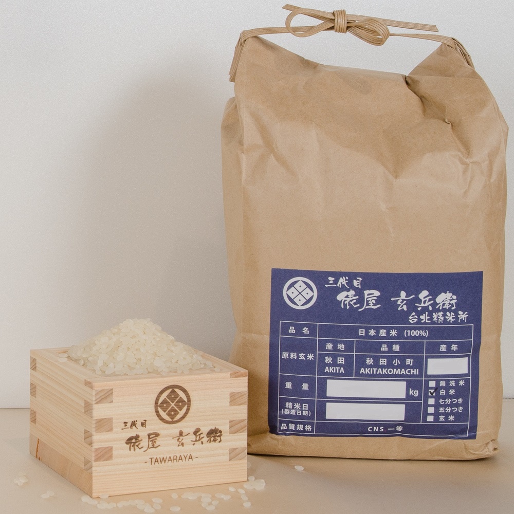 一個木盒裝有堆積的白色米粒，旁邊是一個大型牛皮紙包裝的米，包裝上有標籤，上面印有日文文字和圖案。