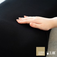 一隻手輕柔地觸碰著黑色的枕套，布料帶有細緻的紋理。右下角有「日本製造 原裝進口」及「王樣」的品牌標誌。