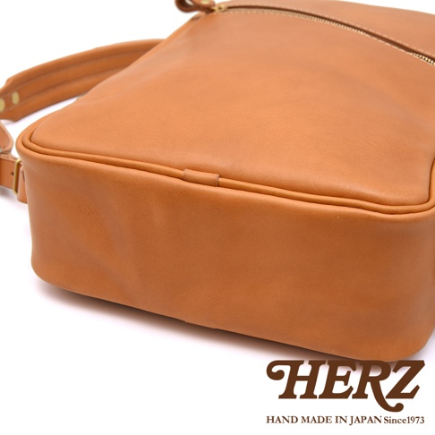 職人手作皮革長方型後背包，採用淺棕色皮革，設有拉鍊開口和可調式肩帶，展現簡約設計。